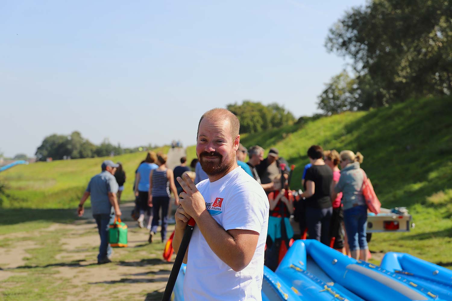 Mann gibt einer Gruppe eine Einweisung für Schlauchboote und hält ein Paddel